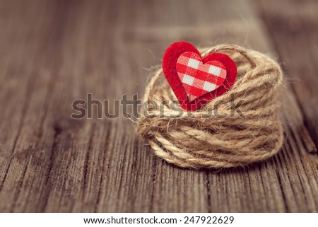 Red valentine\'s day holiday heart in nest on wooden background with retro instagram toning