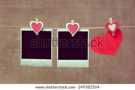 Two polaroid photo frames and heart for valentines day hanging on rope with vintage instagram toning