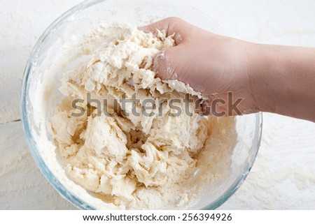 Dough ingredients mixing in bowl with hand
