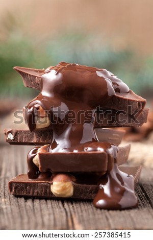 Stack of melted chocolate with nuts on wooden background