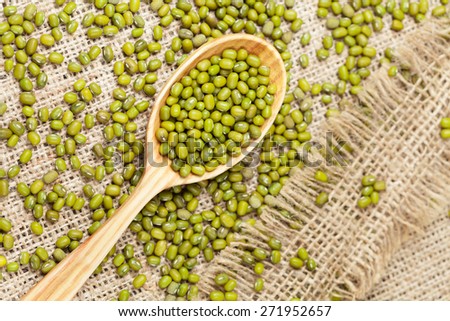 Super foods clean eating dieting organic product mung beans in wooden spoon on vintage textile background