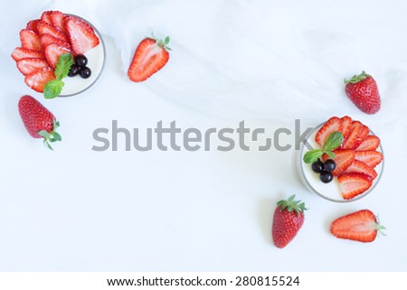 Summer sweet dessert food panna cotta in glass with empty frame for lorem ipsum design text and strawberries on white kitchen table background. Rustic style and natural light