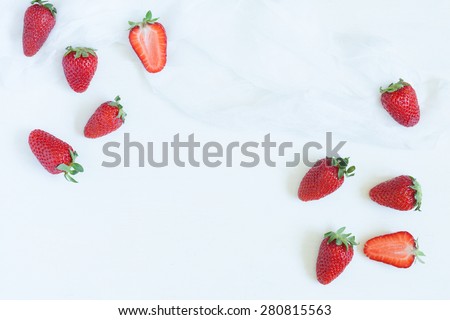 Fresh summer strawberries vegetarian clean eating super vitamin food with empty frame for lorem ipsum design text on white kitchen table background. Rustic style and natural light.