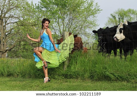 retro pin up girl with her dress caught up on a country farm fence