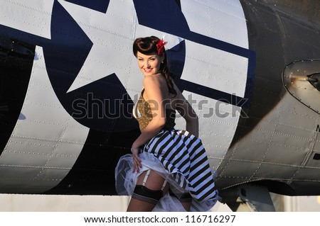 beautiful 1940\'s pin up girl standing in front of a WWII bomber