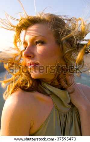 a profile of a young blond woman with the wind blowing her hair in her face