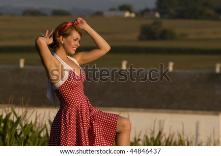 beautiful young woman in a polka dot dress fixing the red bow in her hair