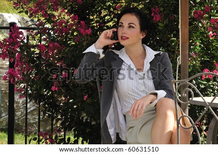 business woman sitting outside in a cafe table and speaking on the phone