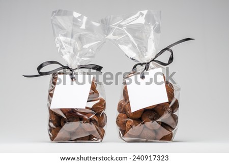 Two luxury plastic bags with elegant black ribbons of chocolate truffles for Christmas gift. Blank label and copy space. Shooting on white background in studio.