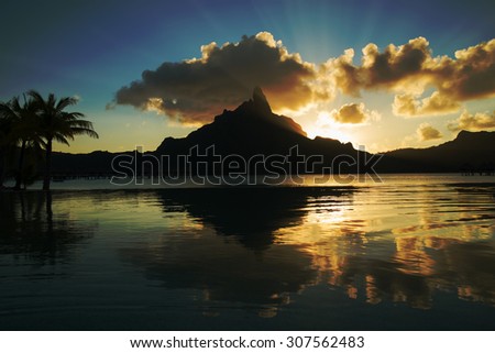 dramatic sunset on Mount Otemanu through lagoon and infinity pool on the tropical island Bora Bora, honeymoon destination, near Tahiti, French Polynesia, Pacific ocean