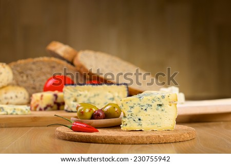 Blue roquefort cheese, olives and red chilli pepper cheese on a wooden serving board