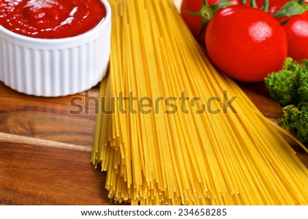 Bunch of italian spaghetti with tomato sauce and tomatoes on wooden brown background