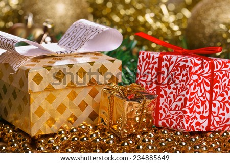 Christmas present boxes with yellow beads with green fir-tree branch on background