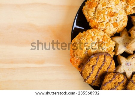 Brown, chocolate and star-shaped cookies on black plate. Empty space for text
