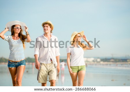 Group of happy young people having a great time on the beach on beautiful summer sunset