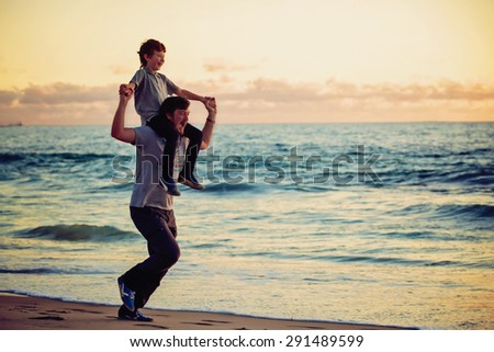 Happy father and son having quality family time on the beach on sunset on summer holidays. Lifestyle, vacation, happiness, joy concept