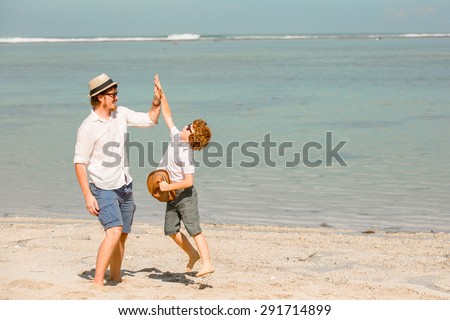 Hipster father with beard and red haired son playing on the beach at the summer day. Vacation, happy and friendly family, holidays concept