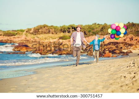 Happy father and son having quality family time on the beach playing with balloons on summer holidays. Lifestyle, vacation, happiness concept