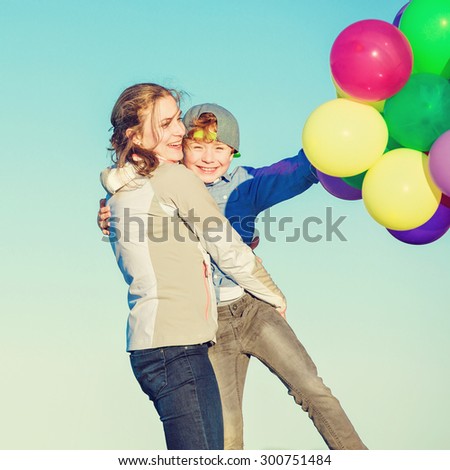 Happy mother and son having quality family time on the beach playing with balloons on summer holidays. Lifestyle, vacation, happiness concept
