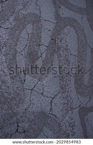 Tar repairs on black asphalt spelling the letter 'M' Stok fotoğraf © 