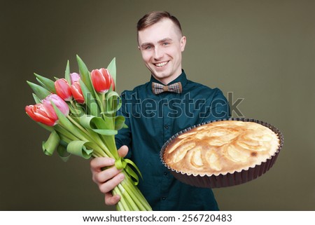 A man in a shirt and tie with a bouquet of pink tulips and pie