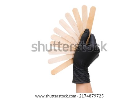 hand in a black glove holds wooden sticks for depilation on white isolated background. fan Foto stock © 