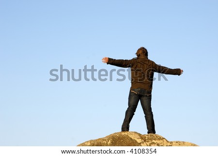 young man with arms wide open and the sky as background