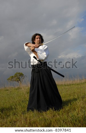 young aikido man with a sword, outdoors