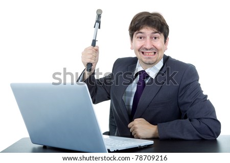 young crazy business man with a hammer smashing a laptop