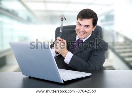 young happy business man with a hammer smashing a laptop