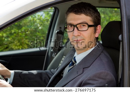 Happy businessman sitting in drivers seat in his car