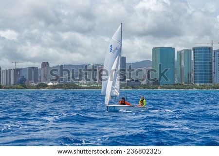 Honolulu, Aug 17, 2014:  Small sailboat moving past Ala Moana Beach Park with a view of Honolulu.  Honolulu, Hawaii, USA.  Aug. 17, 2014.