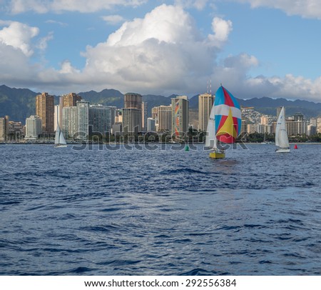 Honolulu, Hawaii, USA, July 1, 2015: Evening sailboat regatta with Waikiki in the background as the sun sets.  Honolulu is a world class sailing destination and home to the Transpacific Yacht Race.