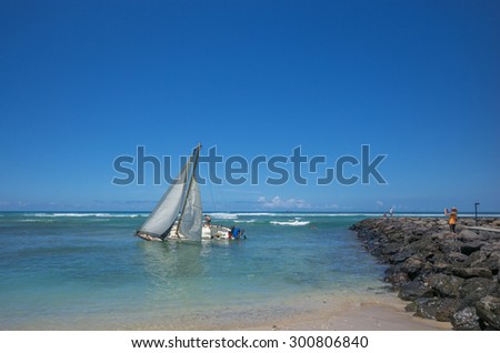 Honolulu, Hawaii, USA, July 29, 2015: Sadness as the crew  climbs out of the beached and sinking sailboat after a valiant effort to save the vessel. Waikiki is a world famous vacation destination.