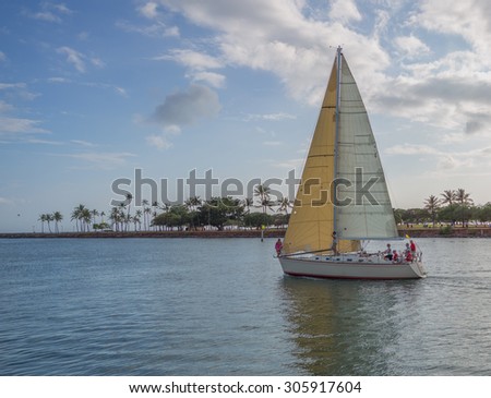 Honolulu, Hawaii, USA, August 14, 2015:  Evening view of a sailboat and crew sailing in the Ala Wai Lagoon.  The Ala Wai Harbor is the largest pleasure boat harbor in Hawaii.