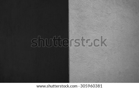 Dawn view of an exterior stucco wall with shadow and light at a 90 degree angle in the wall, and with tones of black white and gray.