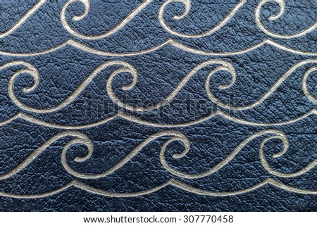 Vintage leather book cover closeup of ocean waves in tones of light gold and surge blue/black.