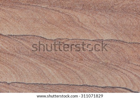 Exterior building sand stone wall with pattern/texture in tones of red, white, and brown.