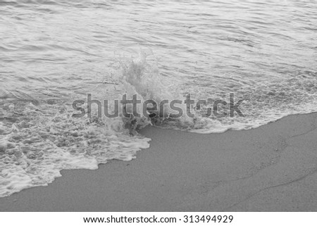 Wave breaking on sand with the focus point on the the breaking wave and a blurred background for use as an advertising backdrop or for use as wallpaper.