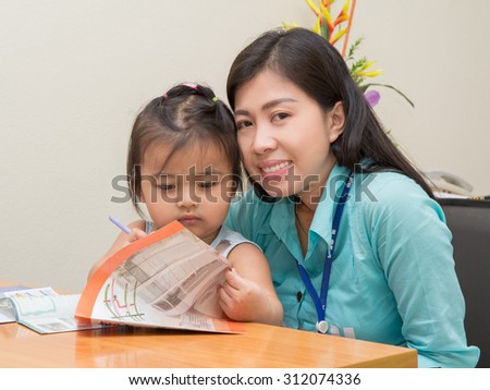 kid girl and her mom reading and writing a book together