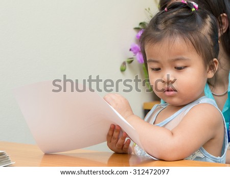 kid girl and her mom reading and writing a book together
