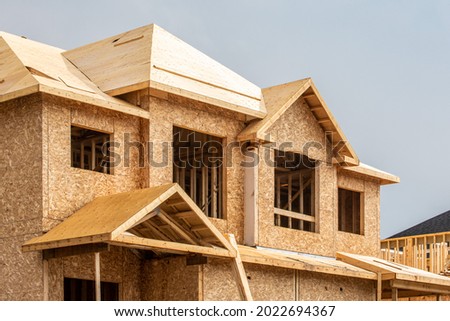 A residential house construction project showing plywood roof and dormer sheathing and oriented strand board or chip board sheathing on the exterior walls ストックフォト © 