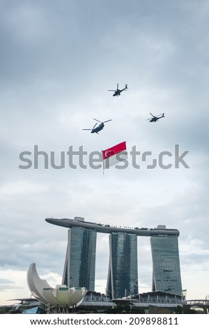 Singapore - August 9, 2014: Singapore National Day helicopter hanging Singapore flag flying over the Sands Hotel