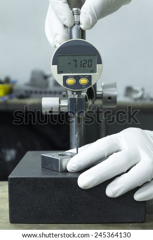 wearing white glove use digital dial gauge measurement on Granite table