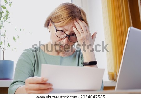 Shocked worried mature woman reading paper document or postal letter feeling frustrated by unexpected news sitting at home indoor. Received bank account balance or bad notice, fine, bankruptcy Imagine de stoc © 