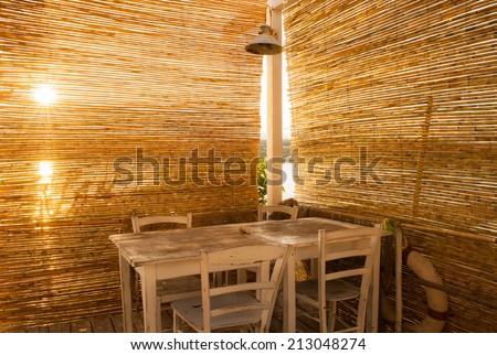 Wooden table of a rustic sea restaurant in a small fishing village at sunrise