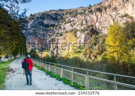 Hiker walking along the trails of the Anapo valley, by the rocky necropolis of Pantalica