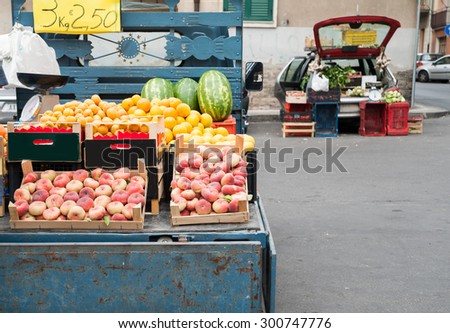 A characteristic Ape car of a street fruit seller full of wooden fruit boxes in a street of Sicily