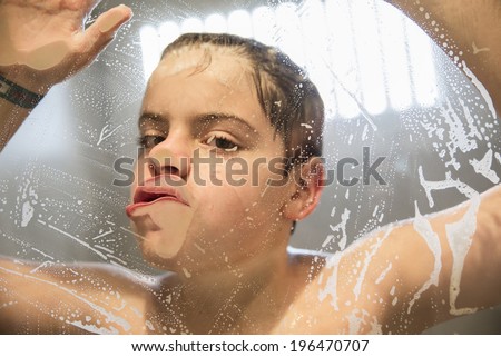 Young  boy (9-10) playing in the shower pressing her face against the glass