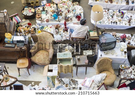Barcelona, Spain - June 18, 2014:  Seller at his post of objects and furniture resale in the most famous flea market in Barcelona, also known as Els Encants or Els Encants Vells
